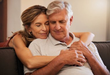 Sarılma, sevgi ve yaşlı çift emeklilik sırasında evlerinin oturma odasında destek veriyorlar. Mutlu yaşlı adam ve kadın güven içinde kucaklaşıyorlar, kanepede yardım ediyorlar ve evlerinde birlikte mutlular..