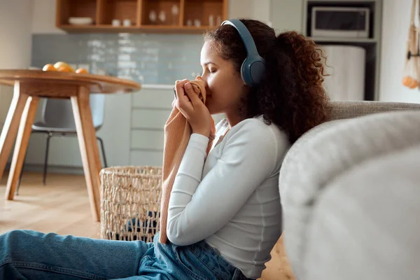 Young woman listening to music in headphones. Young woman enjoying the smell of fresh laundry. Woman smelling fragrant clean clothing. Housework smells so good. A clean house always smells good.
