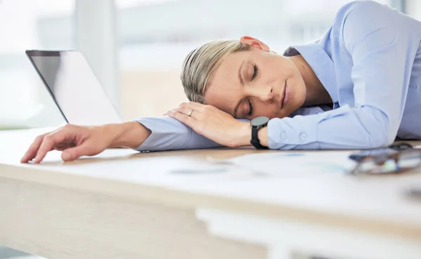 Close up of young caucasian businesswoman feeling tired and sleeping on the desk of a call center in a office. Female wearing wireless headset suffering from burnout.