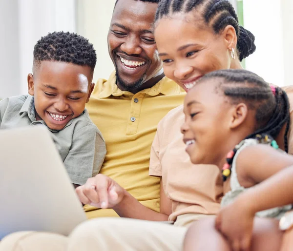Its family movie day. a young family sitting on the sofa together at home and using a laptop
