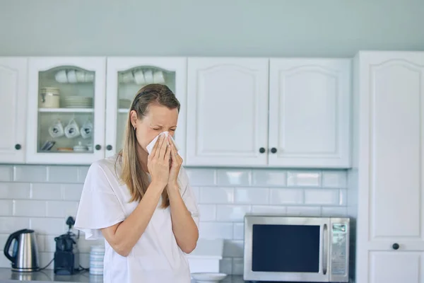 Chora Biała Kobieta Trzymająca Chusteczkę Dmuchająca Nos Stojąc Kuchni Domu — Zdjęcie stockowe