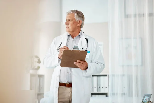 身穿白色实验室外套的沉思的成熟男性高加索医生 凝视着窗外 思考或思考 一位老人拿着一个有病历的剪贴板 看上去很体贴 — 图库照片