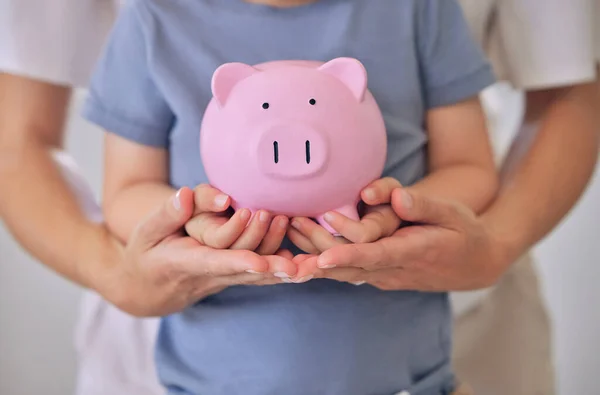 Family, children, money, investments and people concept - close up of mother and daughter hands holding pink piggy bank. Parent teaching her child about savings, future planning and a positive habit.