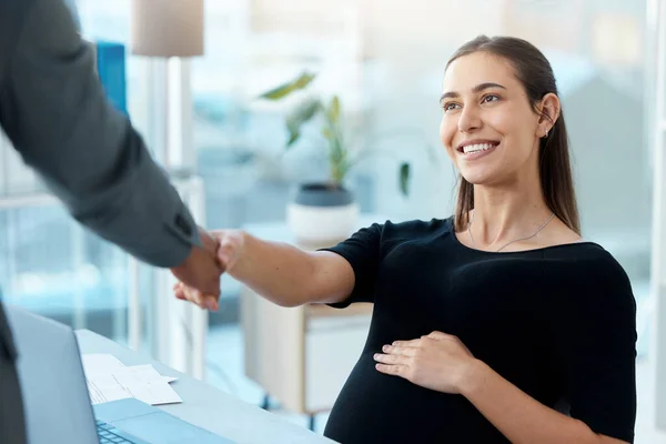 Everyone wants to wish her well before her leave. a pregnant businesswoman shaking hands with a businessman in an office