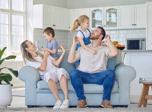 Happy and cheerful caucasian family of four smiling while relaxing together at home. Loving parents playing with their little son and daughter. Siblings sitting with their mom and dad.