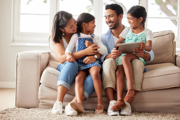 コンテンツ幸せな家族は デジタルタブレットを使用しながら笑顔とソファの上で一緒に家で何を見るかを選択します — ストック写真