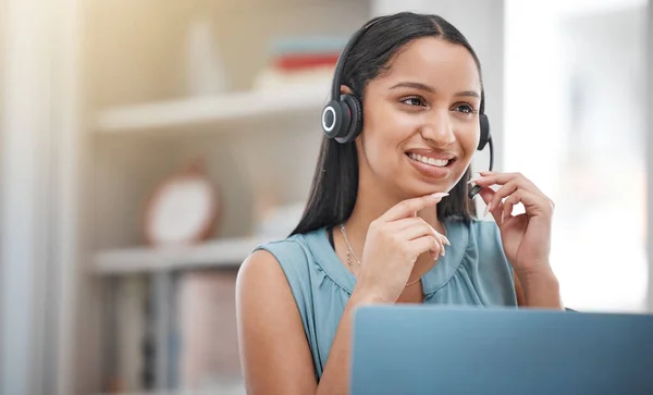 One young hispanic happy and cheerful female call center agent wearing a headset and working in customer service at work. Face of a hispanic woman answering calls working at a call centre on a laptop.