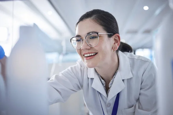 One cheerful caucasian medical scientist wearing glasses and looking at a medicine vial in a laboratory. Healthcare pathologist discovering a cure in a clinic. Controlling diseases with science.