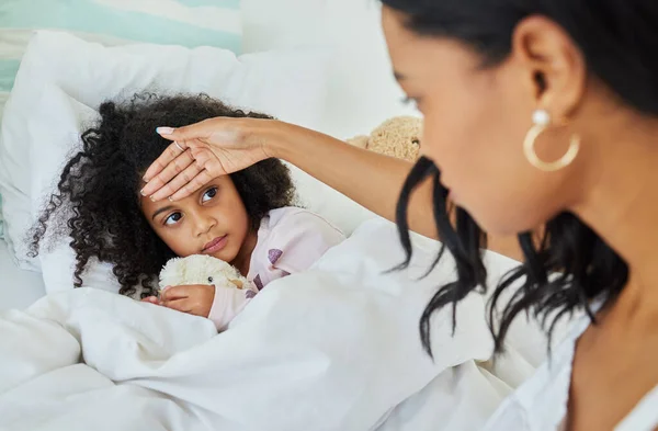 I think you have a fever. a young mother looking after her sick daughter at home