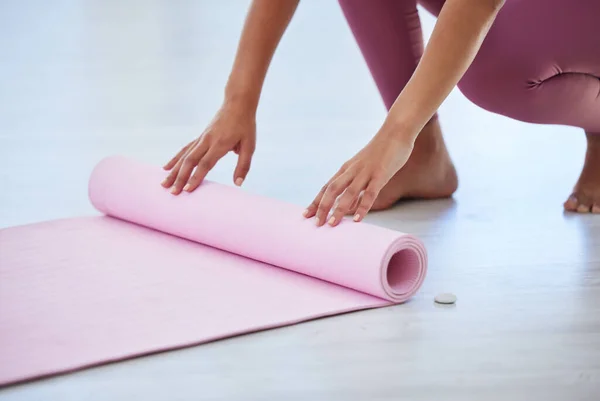 Lets get started right away. Closeup shot of an unrecognisable woman rolling an exercise mat on the floor in a yoga studio