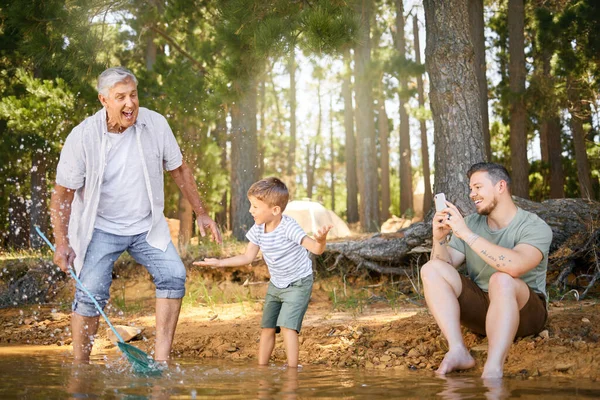 They will each have these great moments to cherish. a little boy having fun with his father and grandfather at a lake in a forest