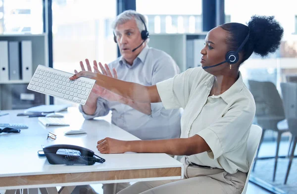 How can I be expected to work with faulty equipment. a young call centre agent angrily throwing a computer keyboard while working in an office