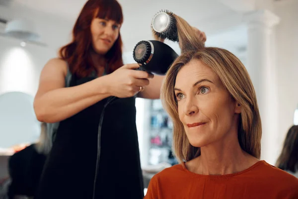 小企業 美容室 高齢者の女性のセルフケアは ブラシやヘアドライヤー付きの美容師によって髪の専門的なスタイルを取得します 成熟したクライアント ヘアケアスタイリスト現代的な髪型とフォーカス顧客 — ストック写真