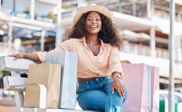 Black woman, retail shopping bag and outdoor bench break from travel buying, sales and summer market retail fashion promotions in San Francisco California. Happy portrait of wealthy customer spending.