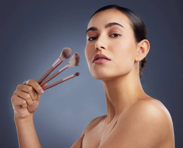Give a girl the right tools and shell create a masterpiece. Studio shot of a beautiful woman holding up a set of make-up brushes