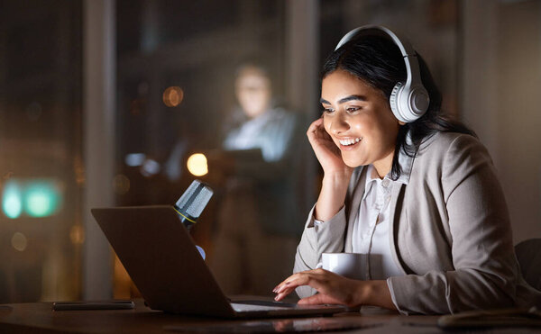 On late nights, music is the best company. an attractive young businesswoman working late at her company offices