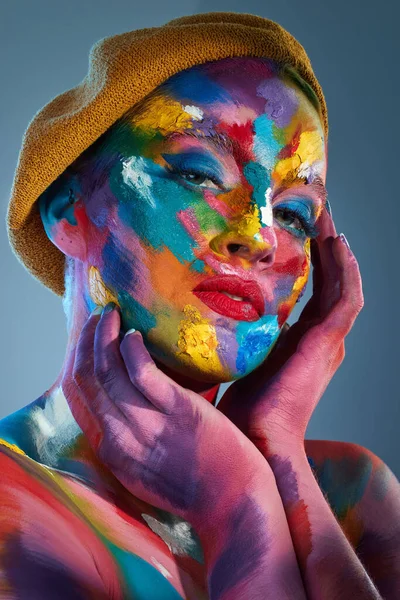 让颜色跳舞 演播室拍摄的是一个年轻女子脸上涂着多种颜色 头上戴着一顶法国帽子的姿势 — 图库照片