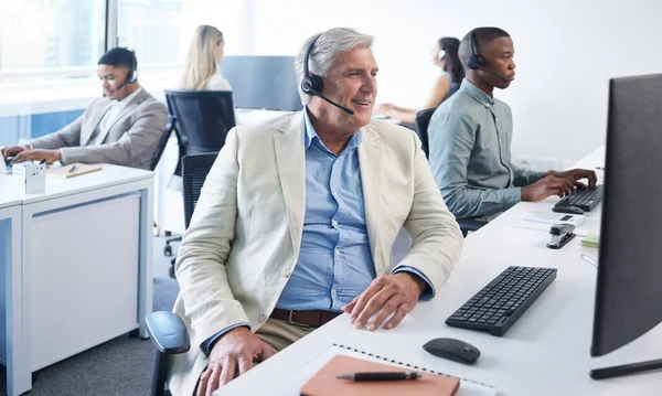 I can certainly fix that for you. a mature businessman using a headset and computer in a modern office