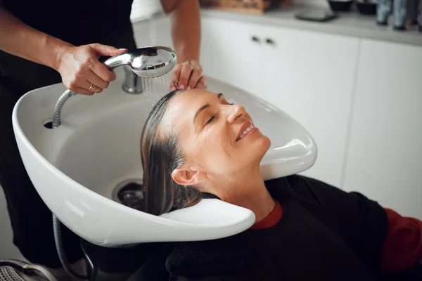 Woman, salon and hair care in wash treatment for beauty, luxury and relax with smile indoors. Happy female enjoying calm relaxation smiling in happiness for clean, service and style by hairdresser.