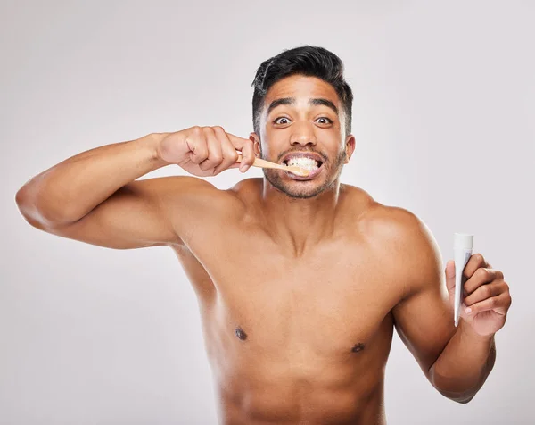 歯磨き粉が一番いい 灰色の背景に歯を磨く若い男が — ストック写真