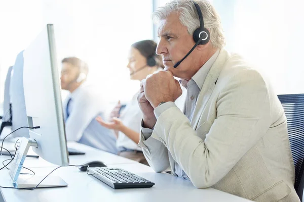 It takes a good listener to deliver good service. a mature man wearing a headset while working in a call center