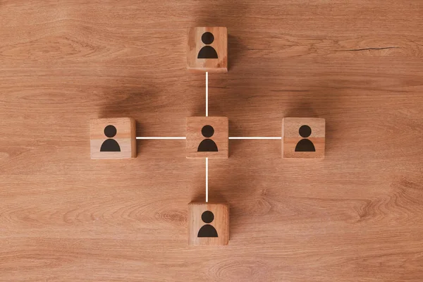 Wood, networking and communication with wooden blocks connected on a brown surface for collaboration or synergy. Marketing, teamwork and connectivity with block icons joined in partnership from above.