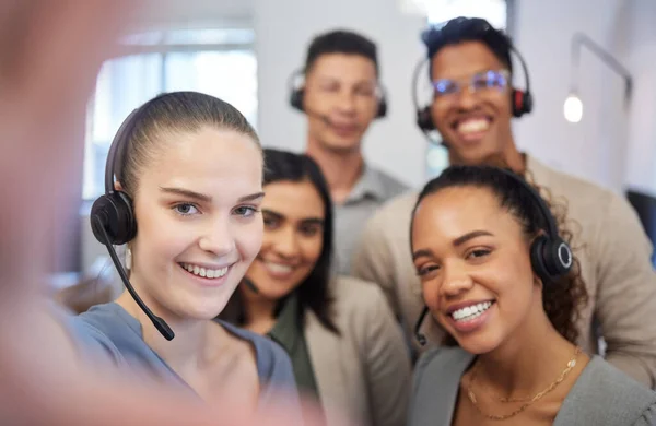 Striving for success alongside quality customer care. Portrait of a group of call centre agents taking selfies in an office