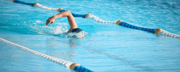 气喘是最好的气喘 在奥林匹克般大小的游泳池里游泳的一个难以辨认的年轻男子运动员 — 图库照片