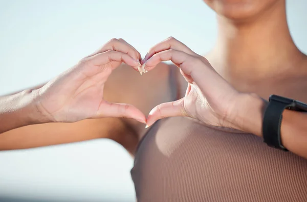 I love the way healthy feels. Closeup shot of an unrecognisable woman making a heart shape with her hands while exercising outdoors