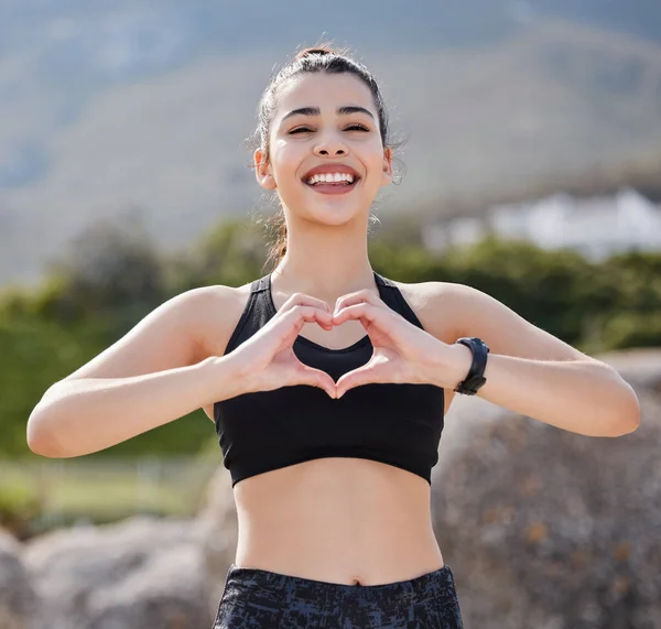 Good times, healthy vibes. Portrait of a fit young woman making a heart shaped gesture after going for a run outdoors