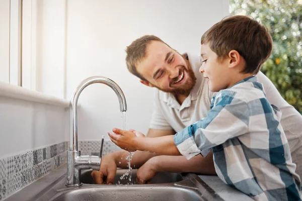 Washing hand is no fun but we can make it fun. a man and his young son washing their hands at home