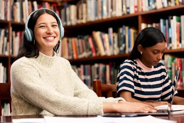 Listening to music gives me more motivation. a young female student studying in a library at college