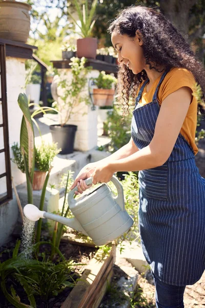 Give them the water they need. a young female florist watering plants at work