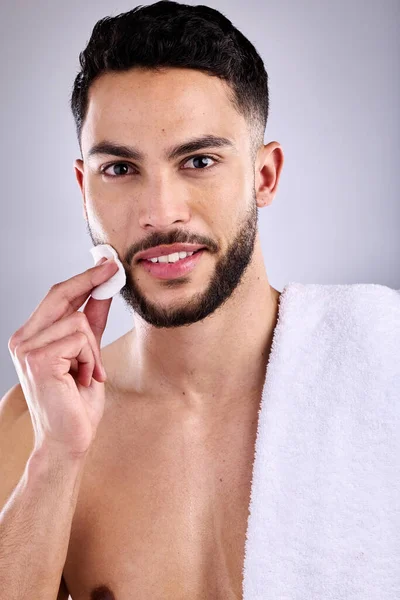 Dont just wash, care for your skin properly. a handsome young man cleaning his face with a cotton pad
