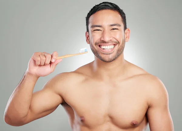 Say hello to my little friend. Studio shot of a handsome young man brushing his teeth against a grey background