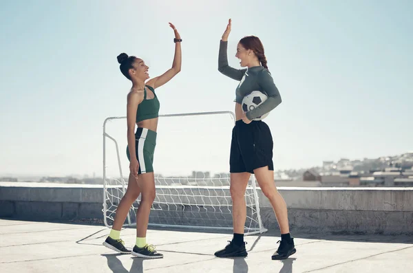 Football, teamwork and high five with women on rooftop for winner, sports training or goals together. Fitness, soccer and exercise with athlete friends and support in workout, success and motivation.