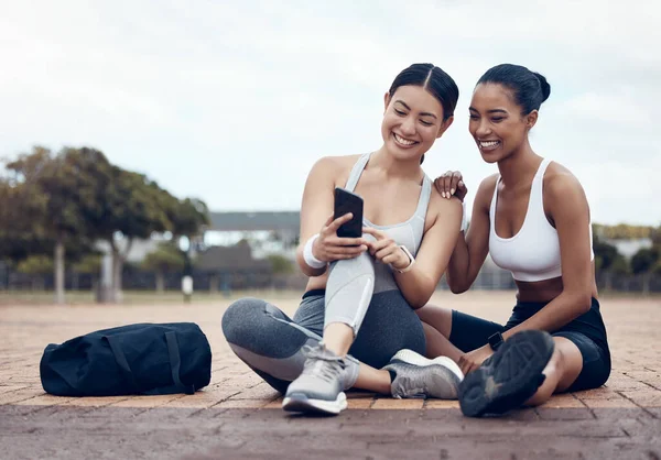 フィットネス インターネット上の女性との電話アプリは ソーシャルメディア モチベーションメッセージや運動の目標について満足しています カーディオワークアウト中の女性ランナーとスマートフォンを持つ選手が屋外を破る — ストック写真