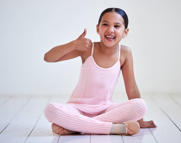 Ballet is awesome. a little girl showing thumbs up in a ballet studio