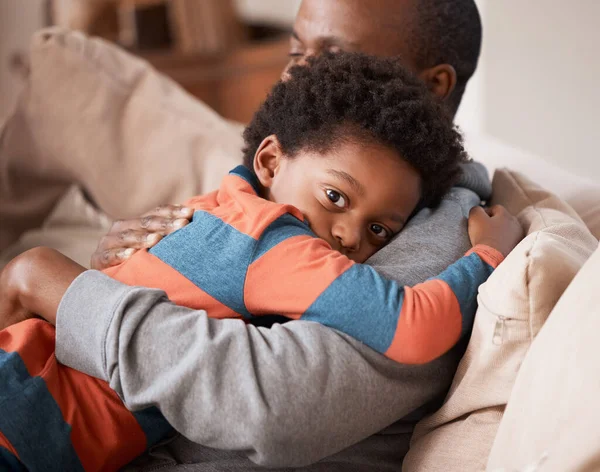 Dad makes him feel safe and loved. Portrait of a little boy hugging his father at home