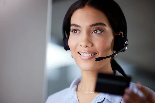 Internet banking was the best thing ever created. a young call centre agent sitting in the office and holding a credit card while using her computer