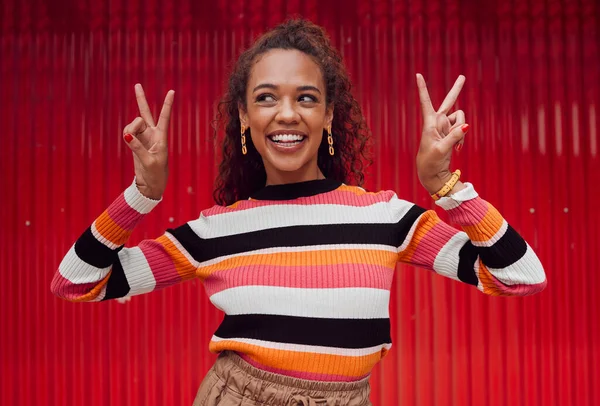 Peace sign, comic and black woman against red wall in the city of Amsterdam for holiday, travel and adventure. Thinking, fashion and young girl with crazy, and funny idea on vacation with smile.