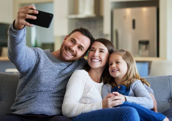 Capture this moment forever. a young family taking a selfie on the couch at home