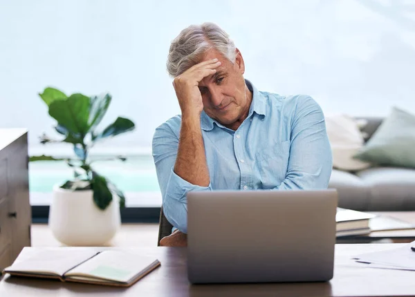 Why do I keep making the same mistake. a mature man sitting alone and feeling stressed while using his laptop to work from home