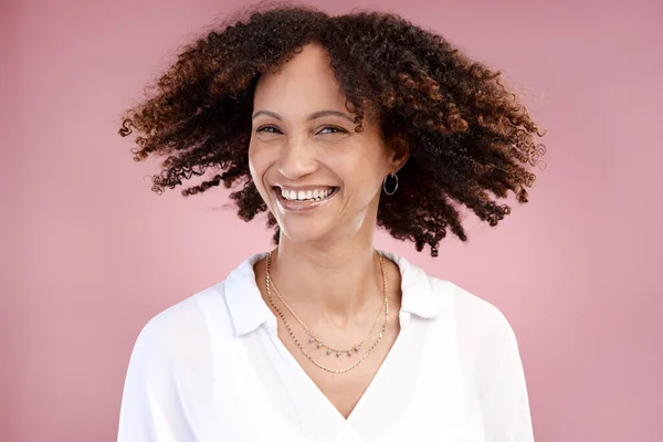 Having a good hair day. Cropped portrait of an attractive young woman posing in studio against a pink background