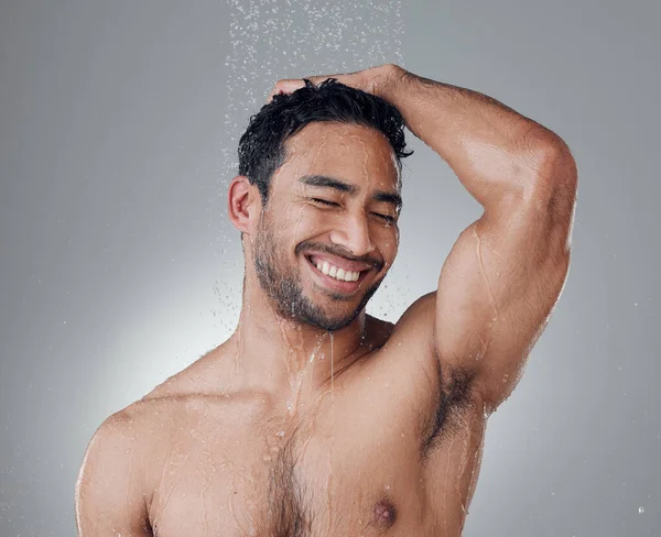 The shower is his happy place. a young man washing his hair in the shower against a grey background