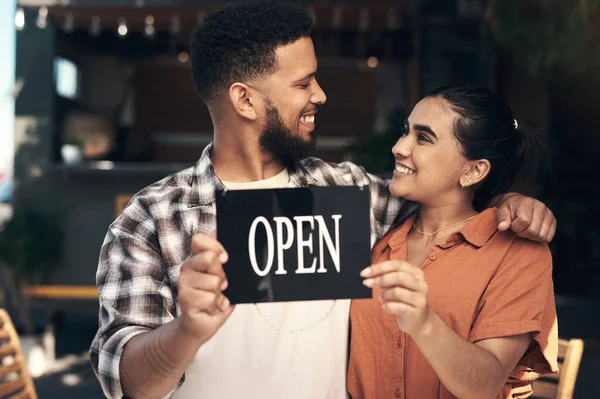 We did it. two young restaurant owners standing outside together and holding an open sign