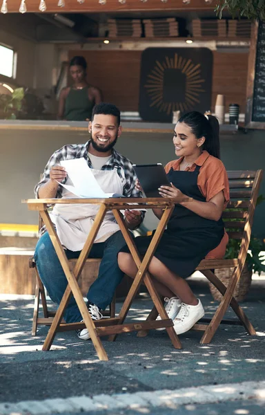 I have a few ideas we can work on. Full length shot of two young restaurant owners sitting outside together and using a digital tablet to plan their menu