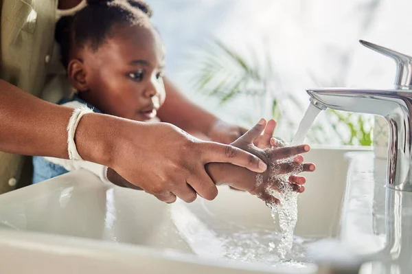 stock image Healthy habits help develop healthy lifestyles. Closeup shot of a mother helping her daughter wash her hands at a tap in a bathroom at home