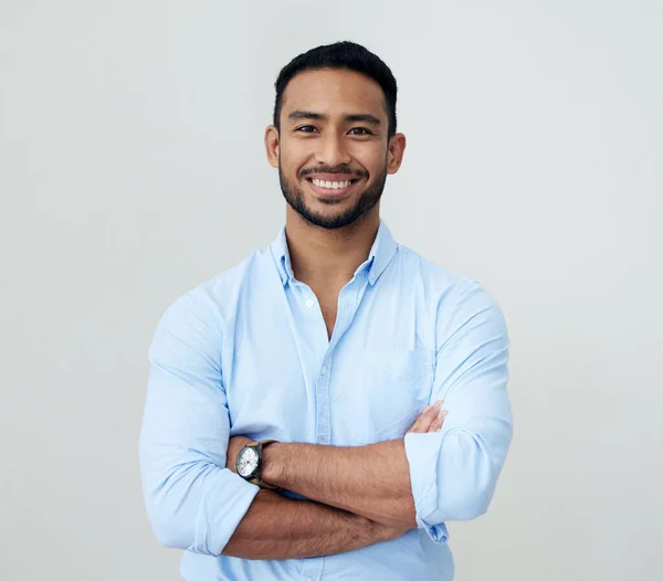 Stay confident as you push through to your goals. Portrait of a confident young businessman standing with his arms crossed against a white background