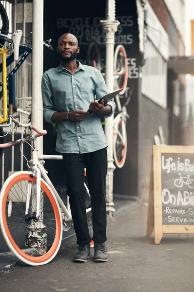 送货地点在哪里 一个英俊的年轻人站在自行车店外面 拿着一块剪贴板 神思恍惚地站在那里的全景照片 — 图库照片
